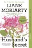 Photo of book The Husbands Secret by Liane Moriarty. White background with pink flower and green stem.